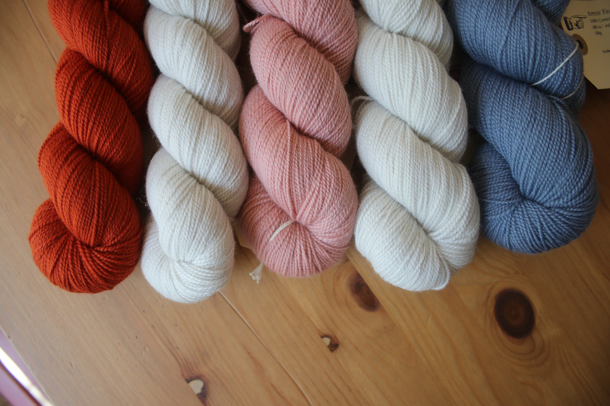 5 skeins of yarn on a wooden table